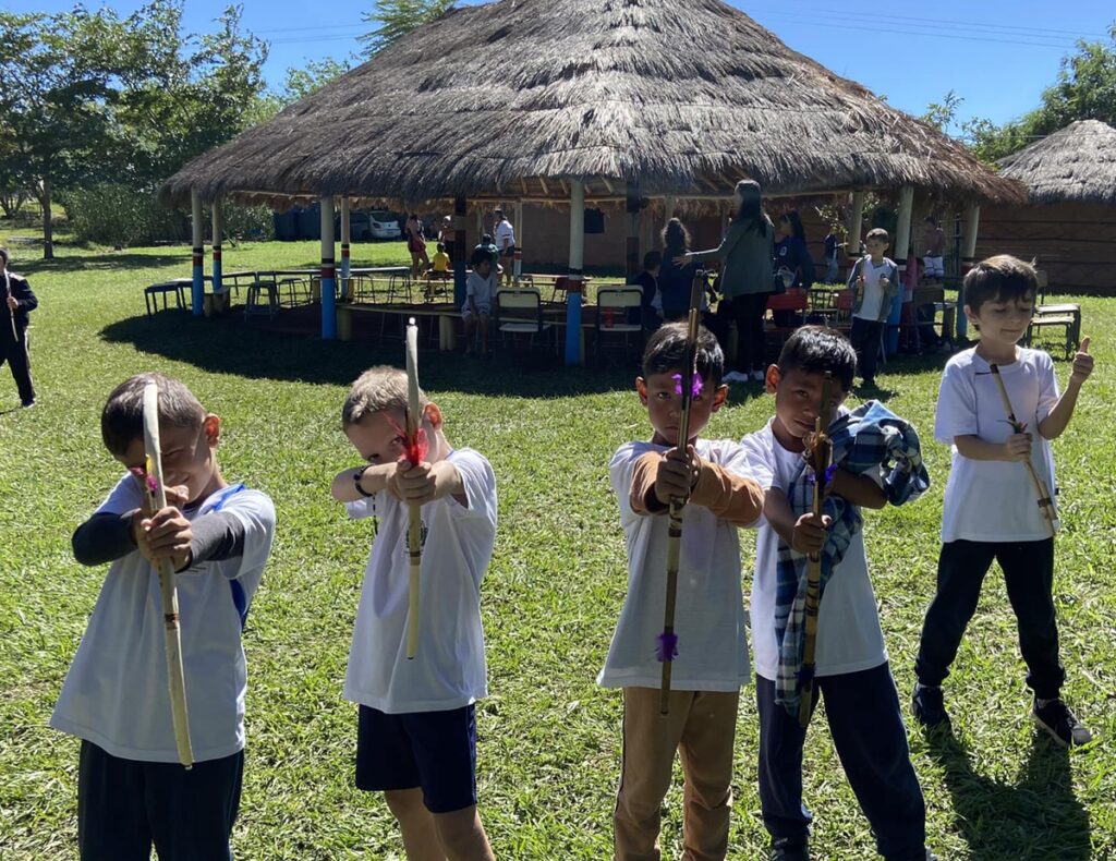 Alunos brincam os arcos utilizados pelos indígenas na aldeia. (Foto: Divulgação)